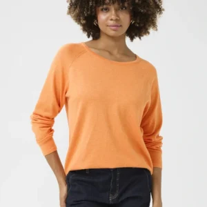 Kvinna bär en långärmad orange topp i viskos och elastan med rund hals och rak passform, matchad med mörka jeans.