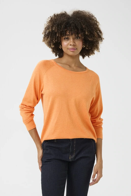 Kvinna bär en långärmad orange topp i viskos och elastan med rund hals och rak passform, matchad med mörka jeans.