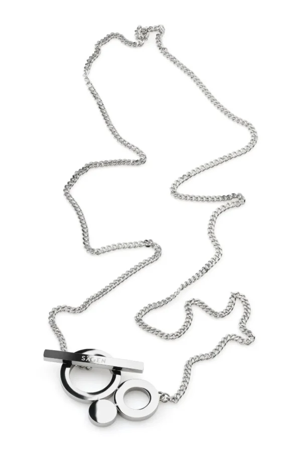 Silverfärgat halsband i polerat stål med grafiskt cirkelhänge och stavlås, liggande mot vit bakgrund.