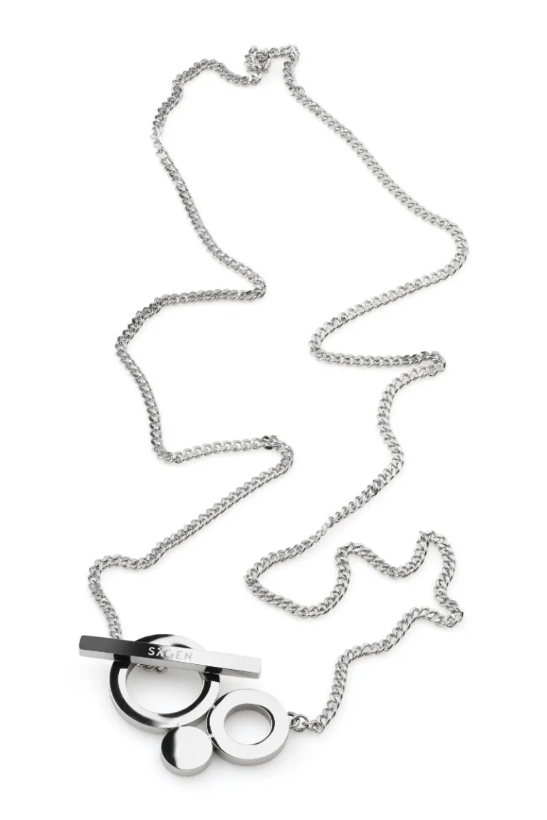 Silverfärgat halsband i polerat stål med grafiskt cirkelhänge och stavlås, liggande mot vit bakgrund.