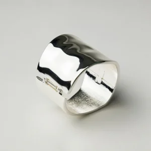 Brett hamrat armband i silverfinish med mjuka former och blank yta, fotograferat mot vit bakgrund.