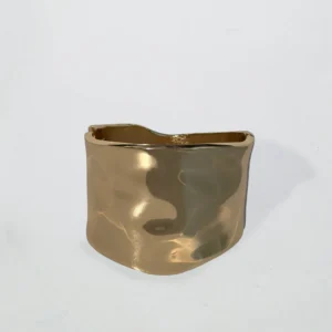 Brett hamrat armband i guldfärg med mjuka former och glänsande finish, fotograferat mot vit bakgrund.