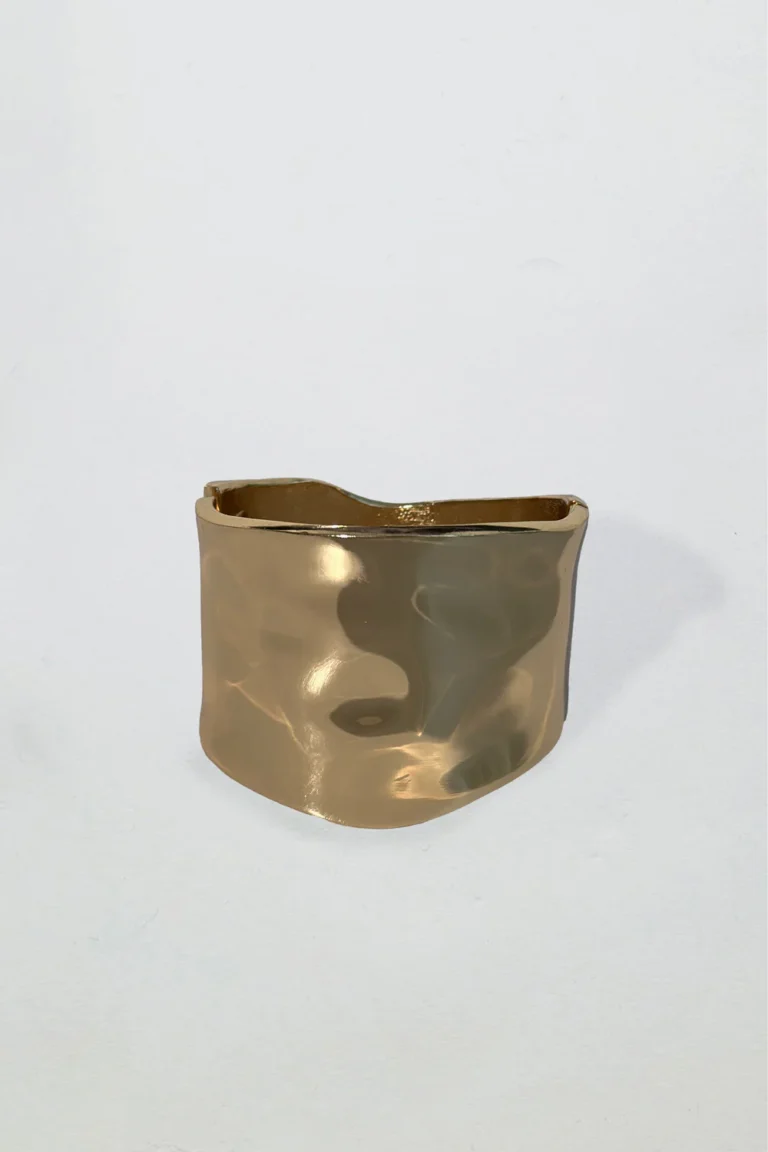 Brett hamrat armband i guldfärg med mjuka former och glänsande finish, fotograferat mot vit bakgrund.