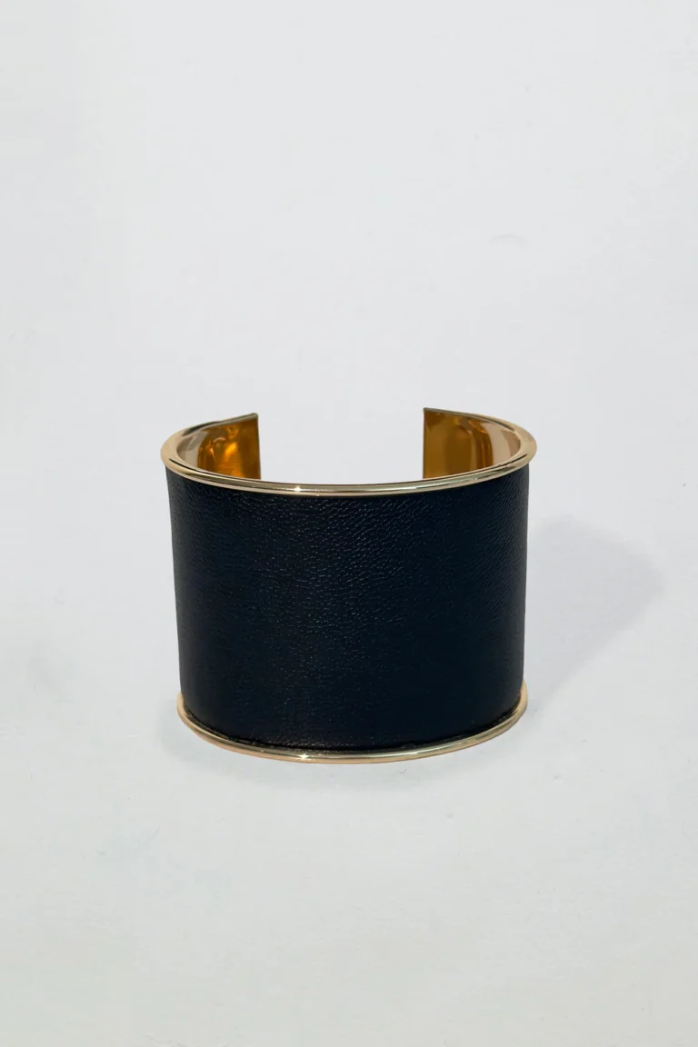 Svart manschettarmband med guldfärgade kanter och öppen design, elegant och modernt mot vit bakgrund.