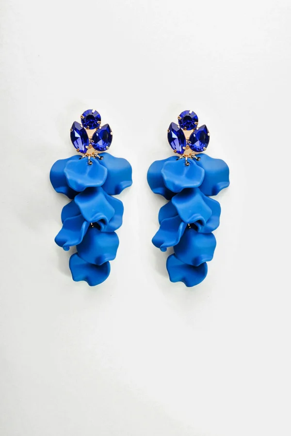 Strong Blue örhängen i blomform med glittrande stenar, placerade mot vit bakgrund. Statement-smycke i akryl och metall.