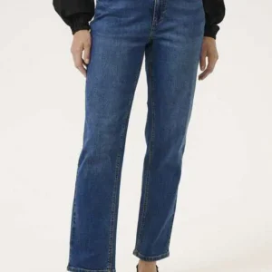 Kvinna i blå momfit jeans med hög midja, stylade med svart blus och klackar.
