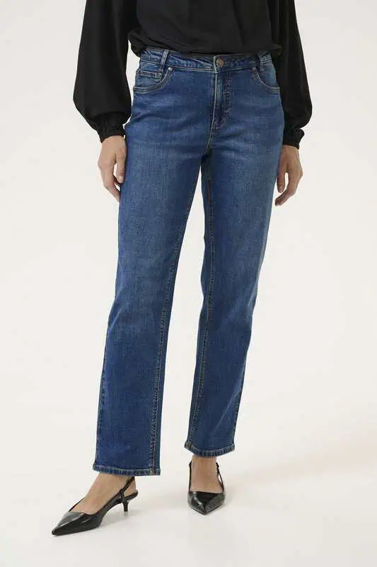 Kvinna i blå momfit jeans med hög midja, stylade med svart blus och klackar.
