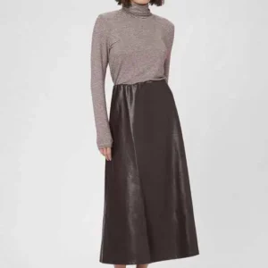 Kvinna bär en chokladbrun PU-middikjol i A-linjeform, stylad med ljusa klackar och långärmad randig tröja.