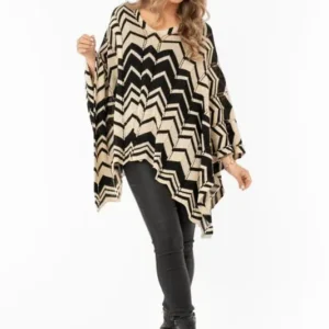 Kvinna i svart- och guldmönstrad cape med zigzag och lurexdetaljer, bärs över svarta byxor.