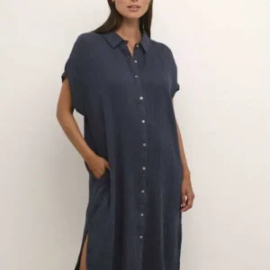 Modell bär blå kaftanklänning från Culture med kort ärm, knäppning och oversize passform.