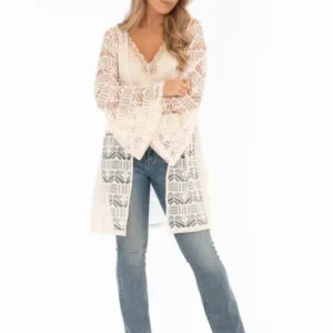 Nella kaftan från Capri Collection i creme med hålmönster och trumpetärmar buren över jeans.