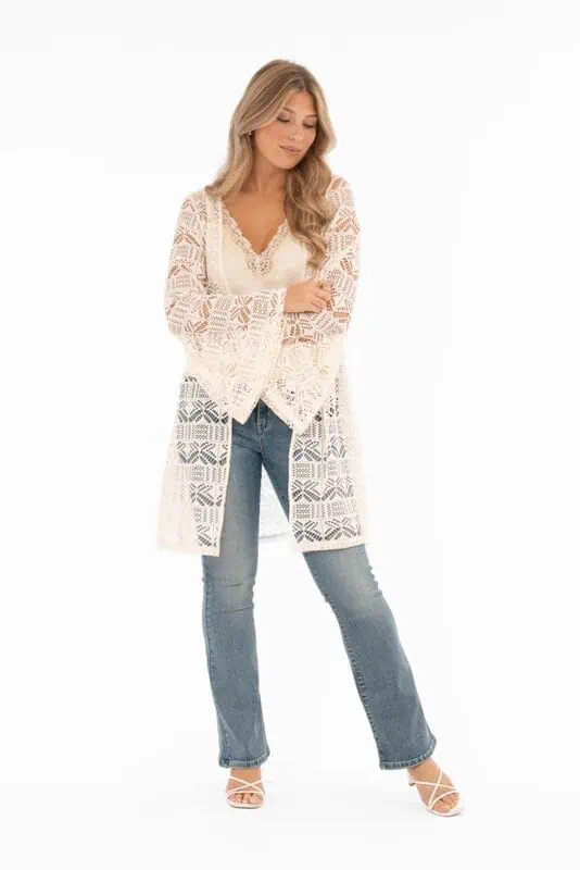 Nella kaftan från Capri Collection i creme med hålmönster och trumpetärmar buren över jeans.