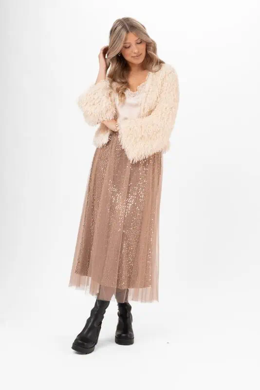 Kvinna i brun Cherie tyllkjol med paljetter, crèmefärgad kofta och svarta boots.