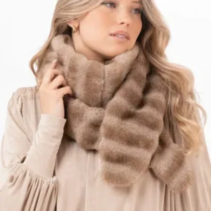 Kvinna med sandbeige Minerva Muffler fuskpälsscarf virad runt halsen över en ljus beige blus.
