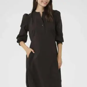 Modell i svart CUAntoinett 3/4 Sleeve Dress från Culture med puffade trekvartsärmar, knappslå vid halsen och sidfickor.