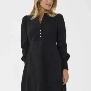 Modell i svart CUloretta Antoinett Dress från Culture, en knälång klänning med långa puffärmar, breda ärmslut och dekorativa knappar vid halsen.