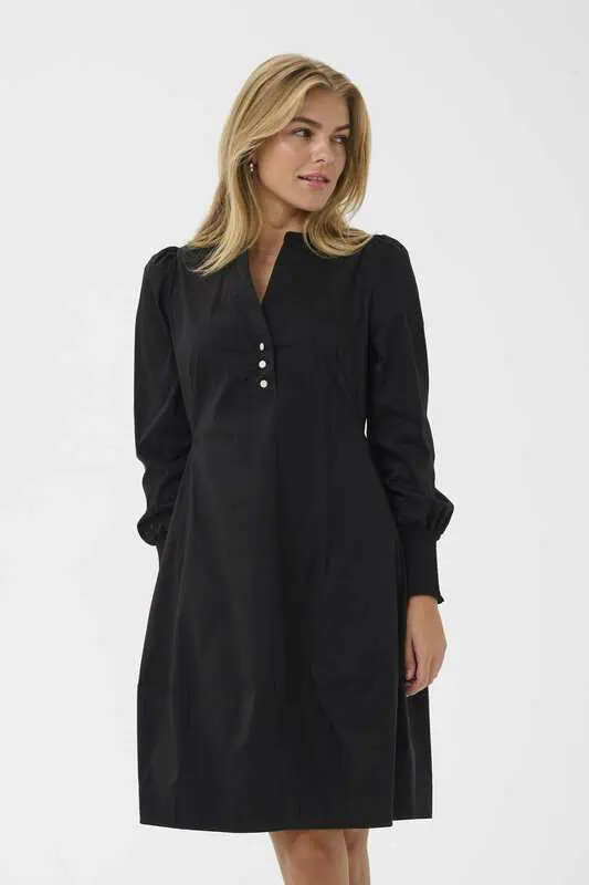 Modell i svart CUloretta Antoinett Dress från Culture, en knälång klänning med långa puffärmar, breda ärmslut och dekorativa knappar vid halsen.